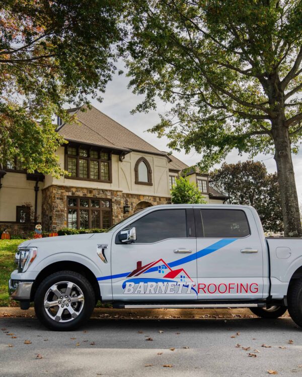 Barnett Roofing branded pickup truck parked in front of a client's house