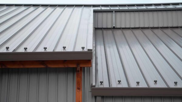 Close-up view of a modern metal roofing and wall with vertical ridges and exposed fasteners, highlighting clean lines and industrial design elements.